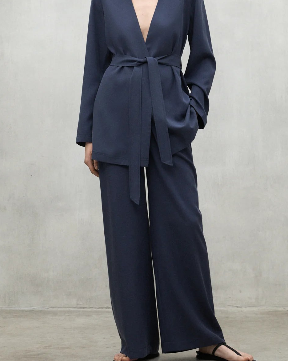 Woman wearing a navy blue suit against a plain background