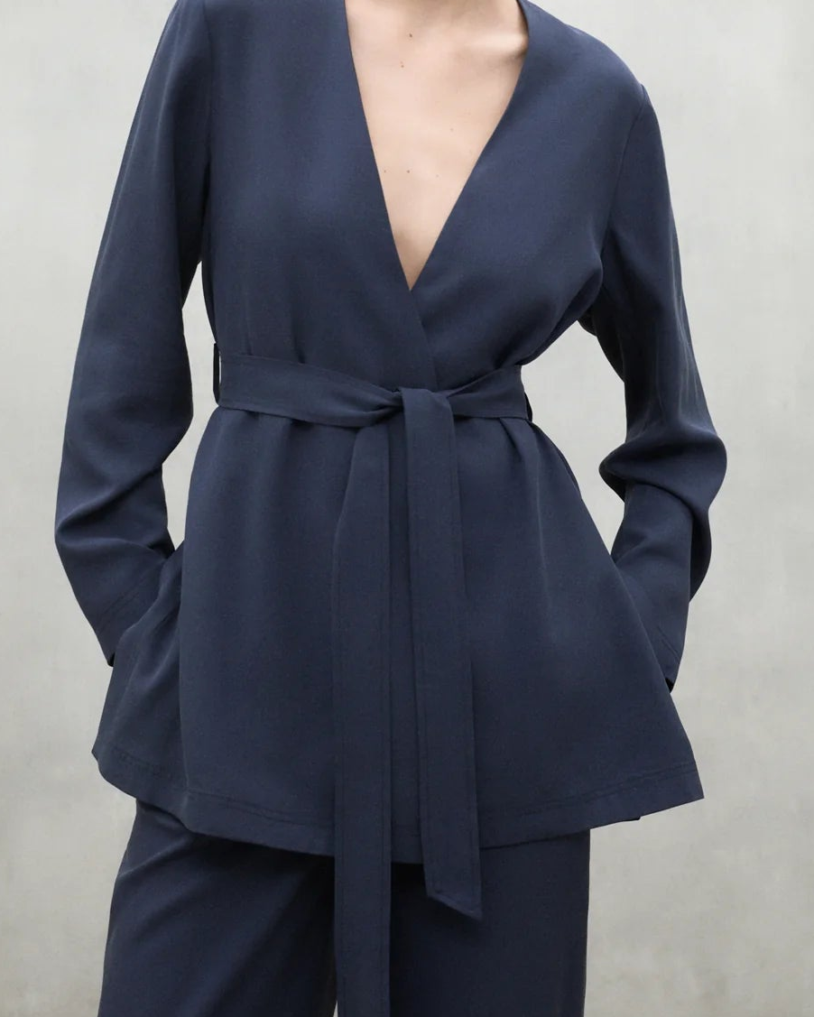 Woman wearing a navy blue outfit against a plain background