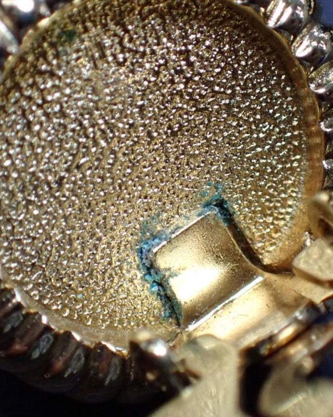 Close-up of a gold and silver pendant on a blue checkered background