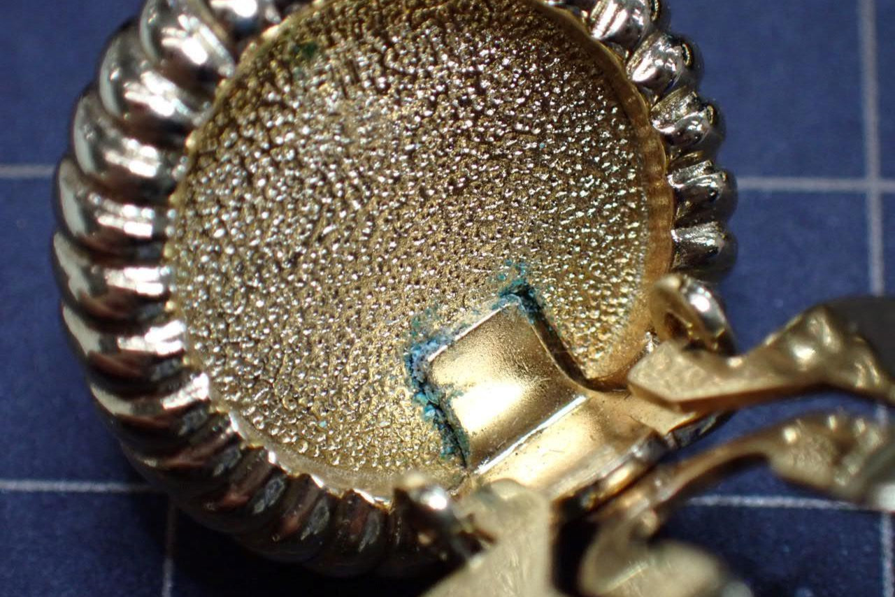 Close-up of a gold and silver pendant on a blue checkered background