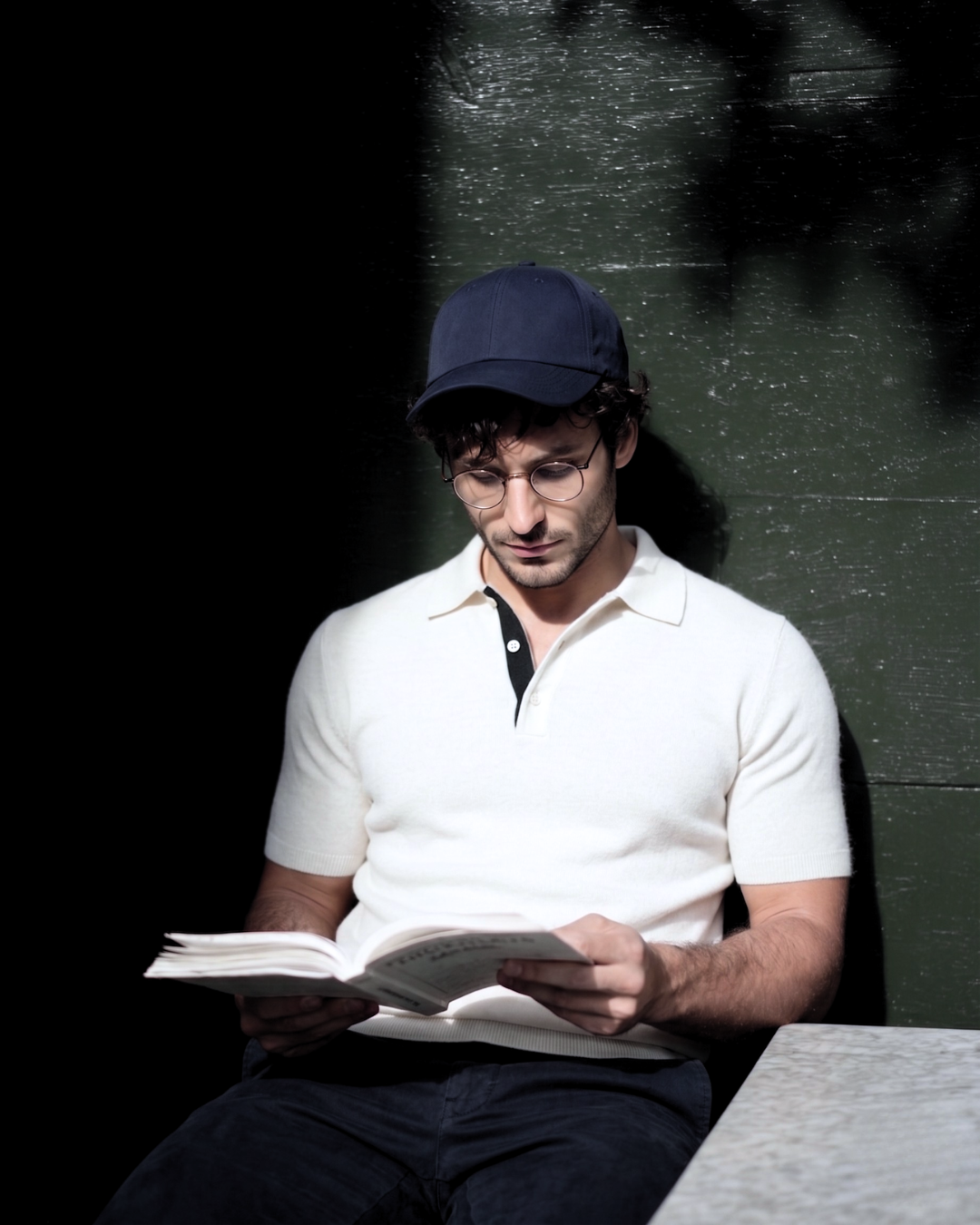 Man reading a book against a dark wall