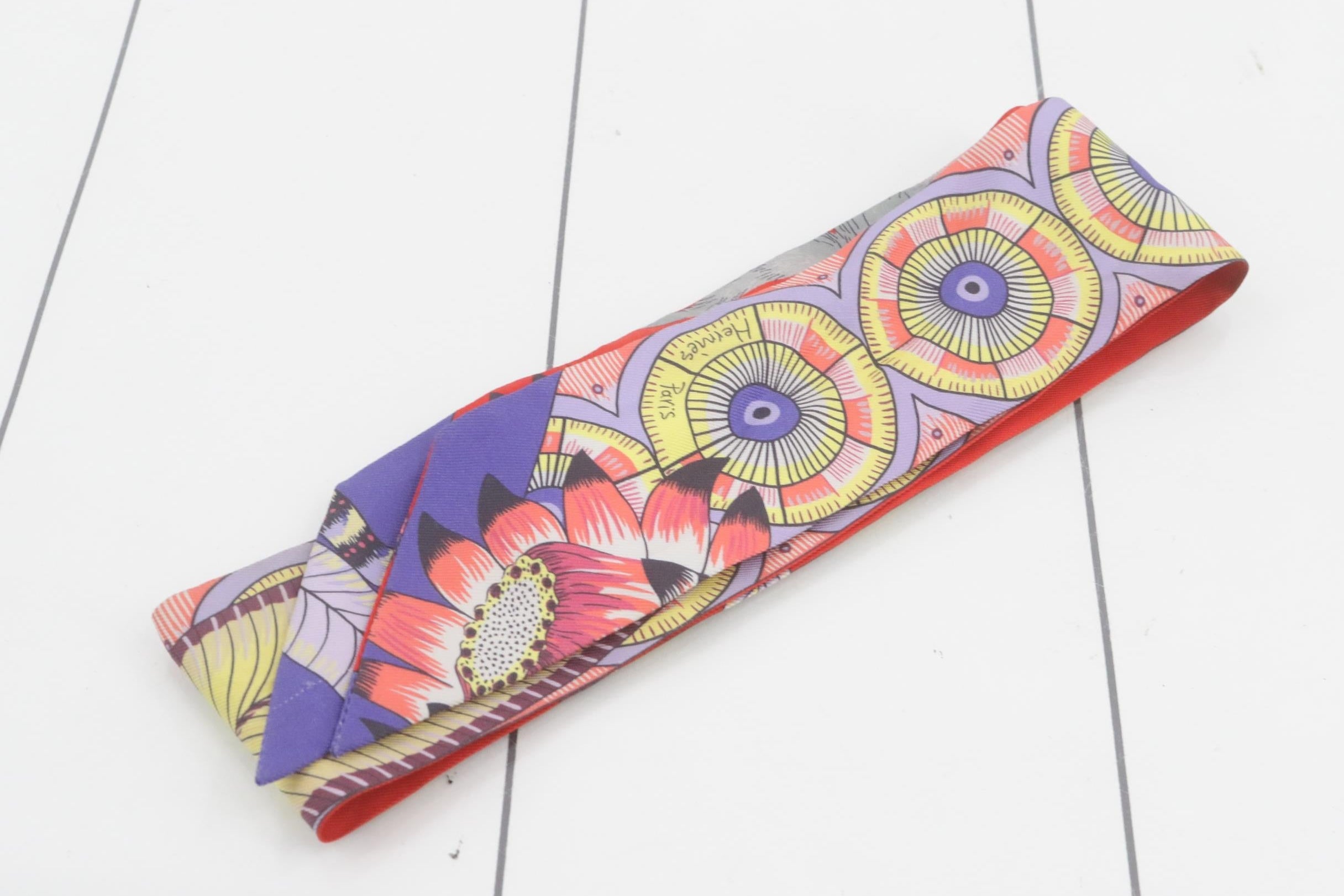Colorful fabric Hermes headband with floral and abstract patterns on a white background