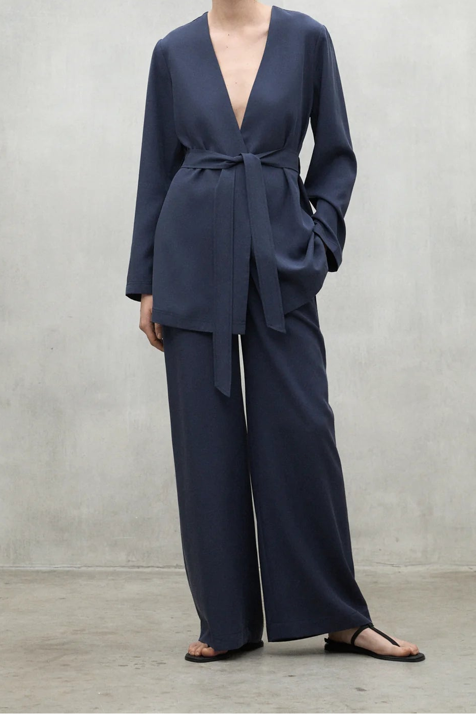 Woman wearing a navy blue suit against a plain background