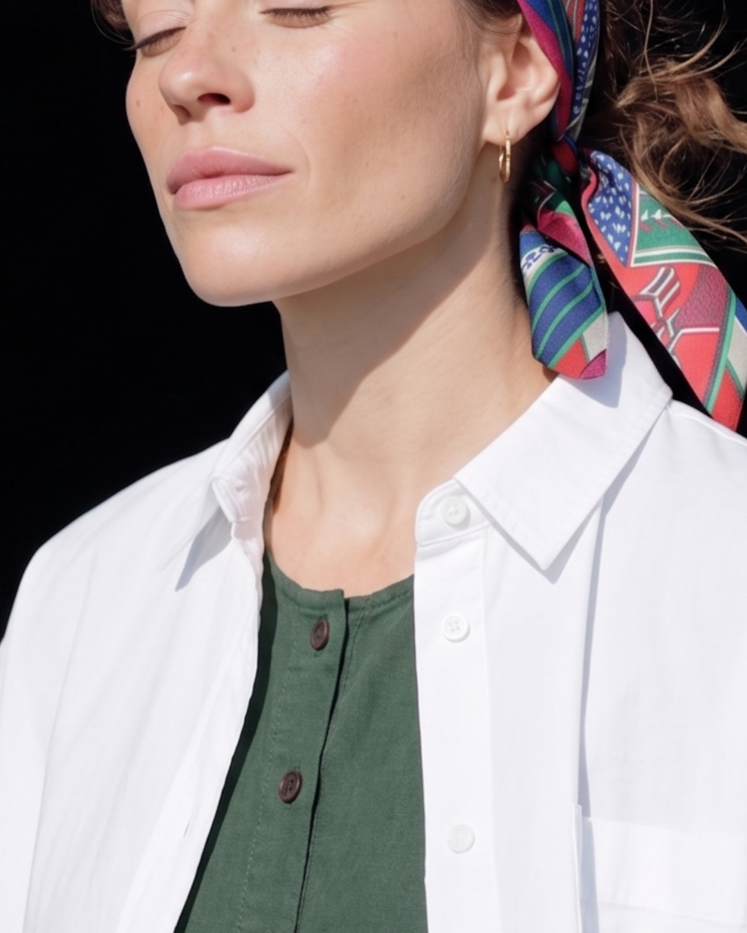 Woman wearing a colorful headscarf with a black background