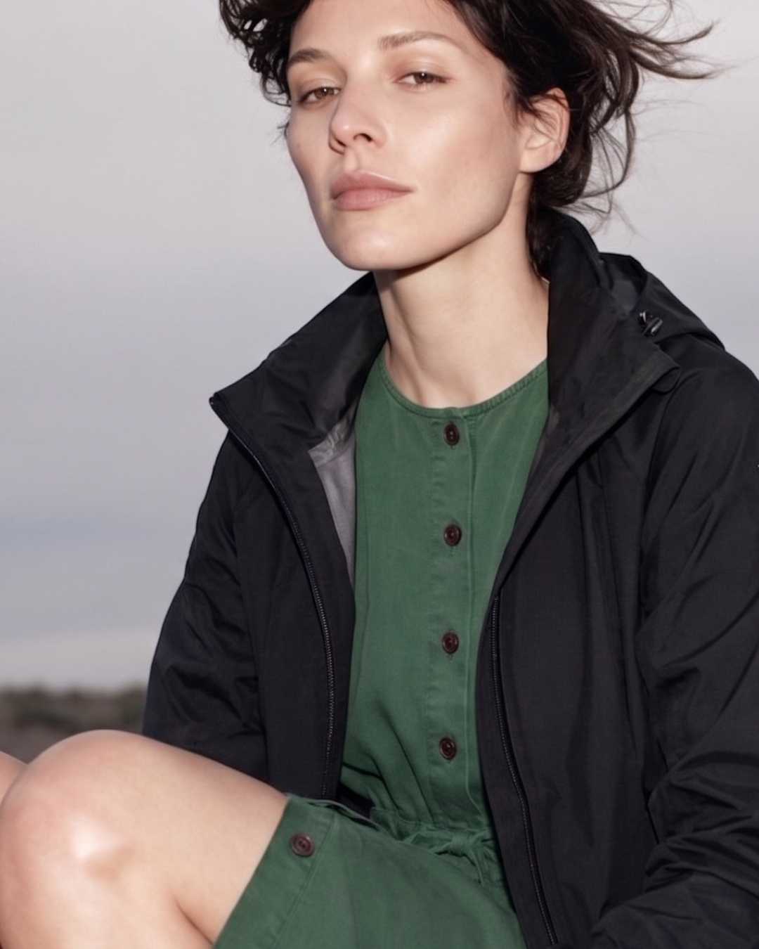 Woman wearing a black coat over a green dress with a blurred background